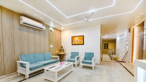 Ein modernes Wohnzimmer mit einer Couch, zwei Sesseln, einem Couchtisch und einem Deckenventilator.