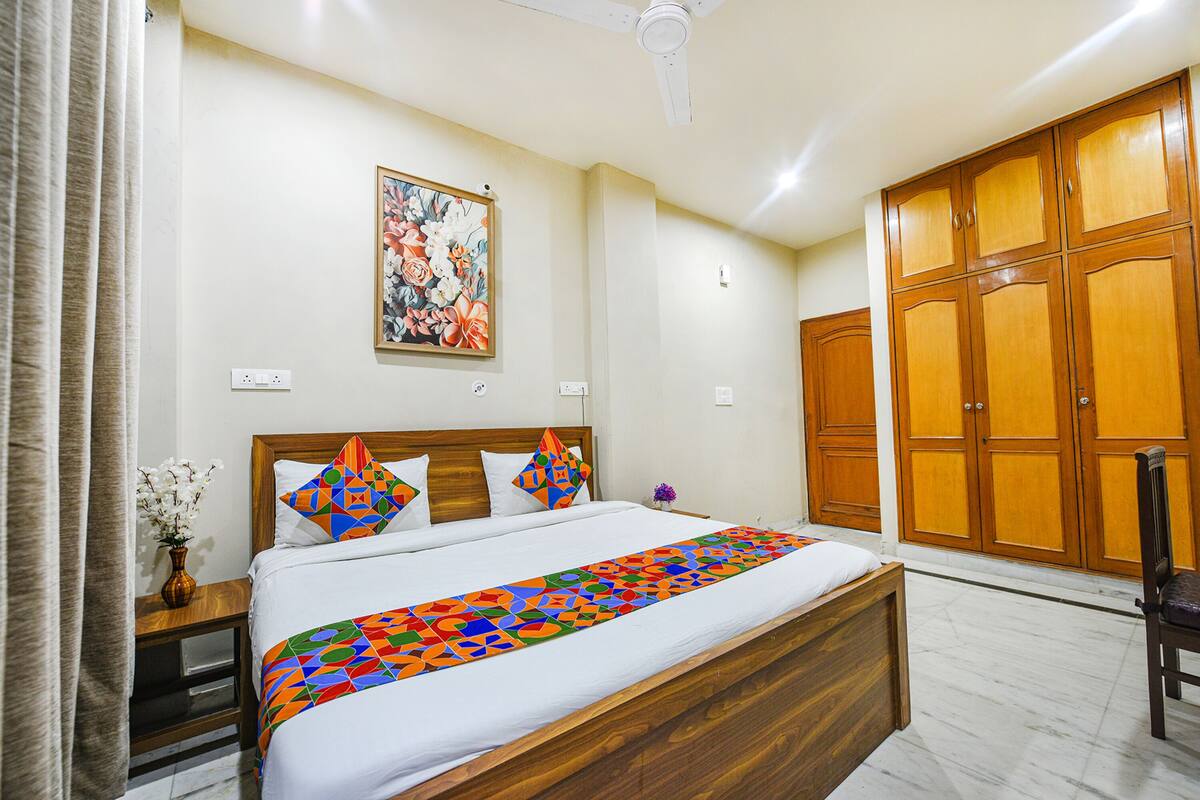 A hotel room with a large bed, wooden wardrobe, and a ceiling fan.
