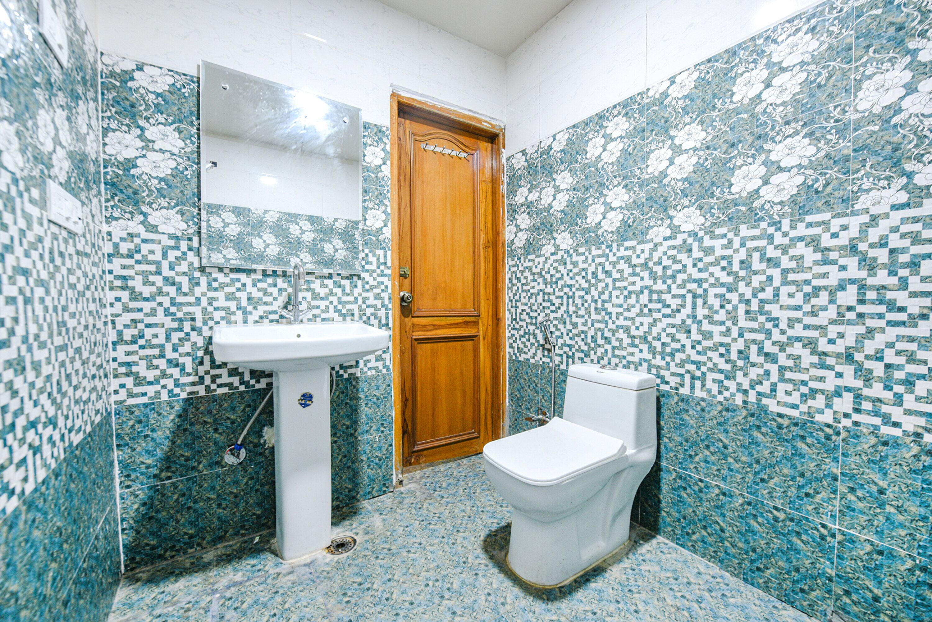 Une salle de bain avec une porte en bois, un lavabo blanc et des toilettes.