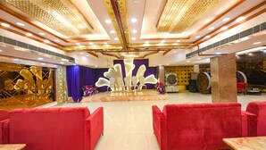 Un amplio salón con asientos rojos, un escenario con sillas doradas y un techo decorativo.