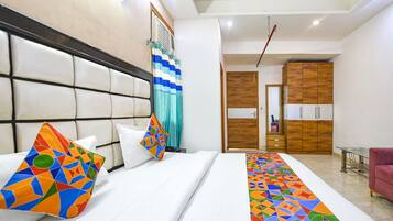 A hotel room with a large bed, a headboard, a wooden wardrobe, and a pink chair.
