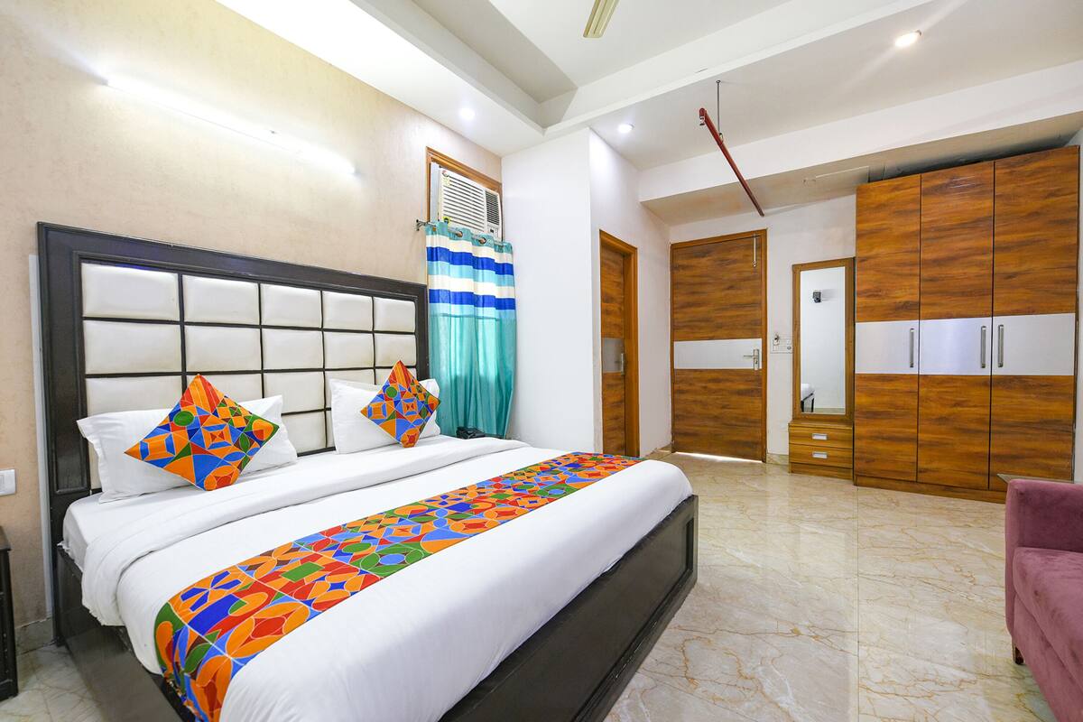 Una habitación de hotel con una cama grande, un armario de madera y un baño con espejo y almacenamiento.