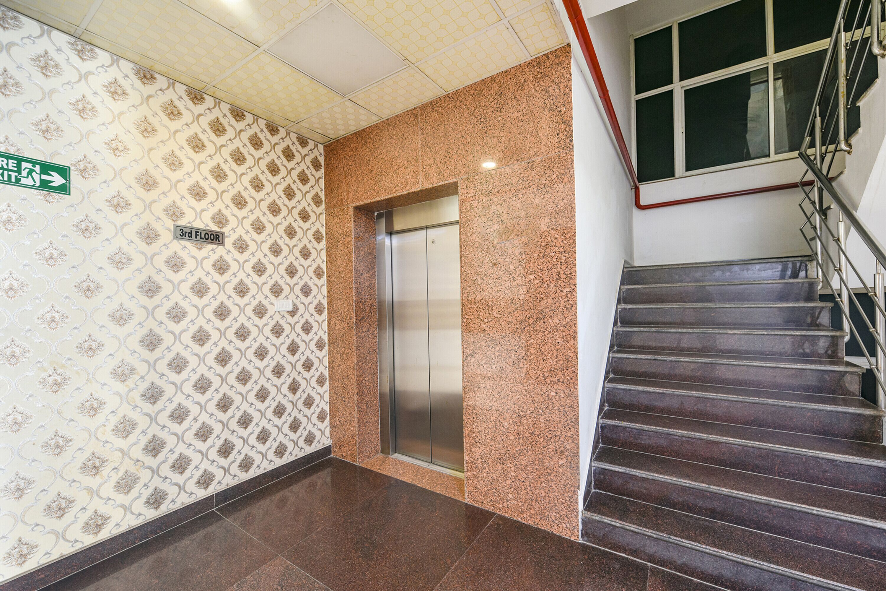 Un couloir avec un mur décoré de motifs, un ascenseur et un escalier.