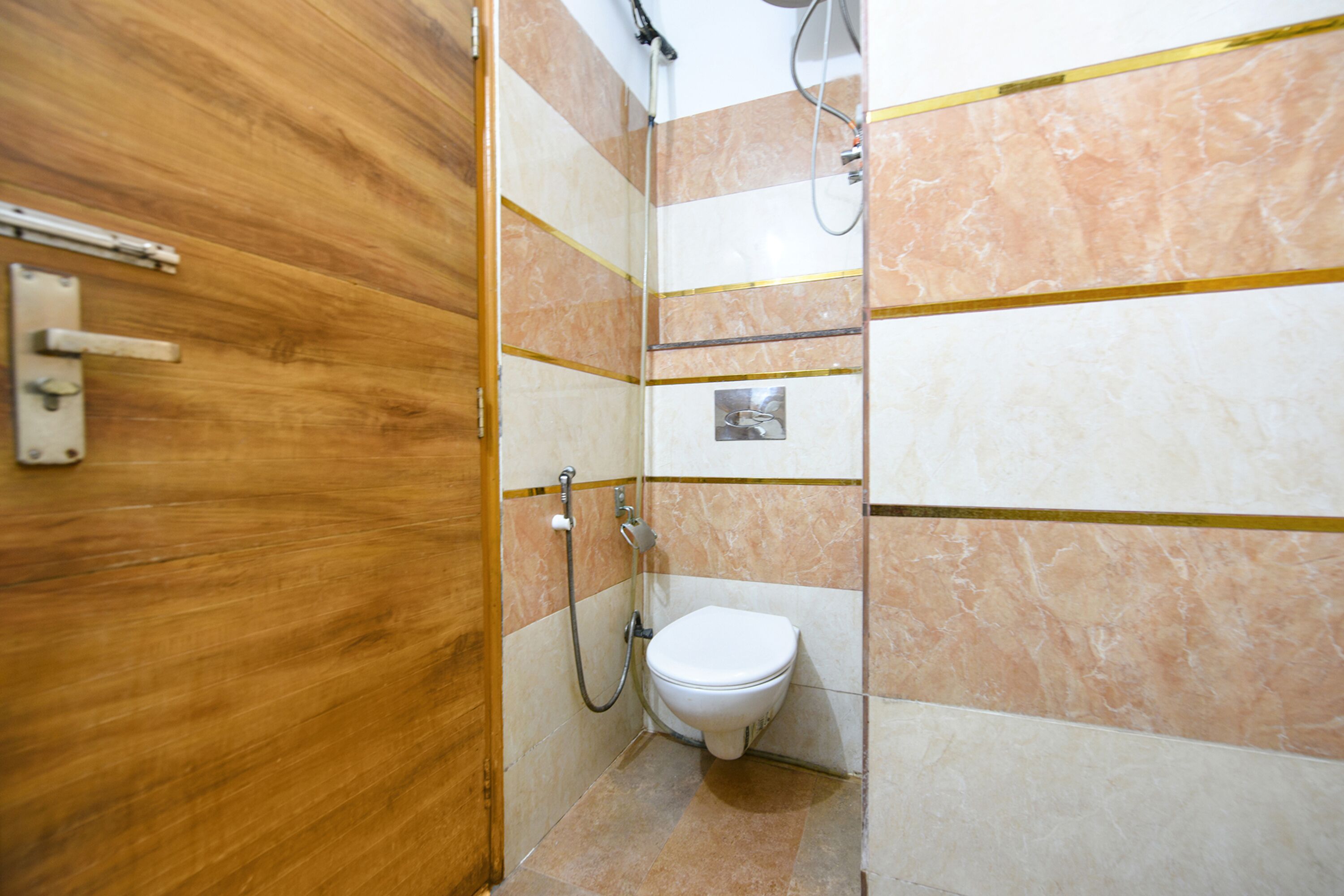A bathroom with a wooden door, a white toilet, and a shower area.