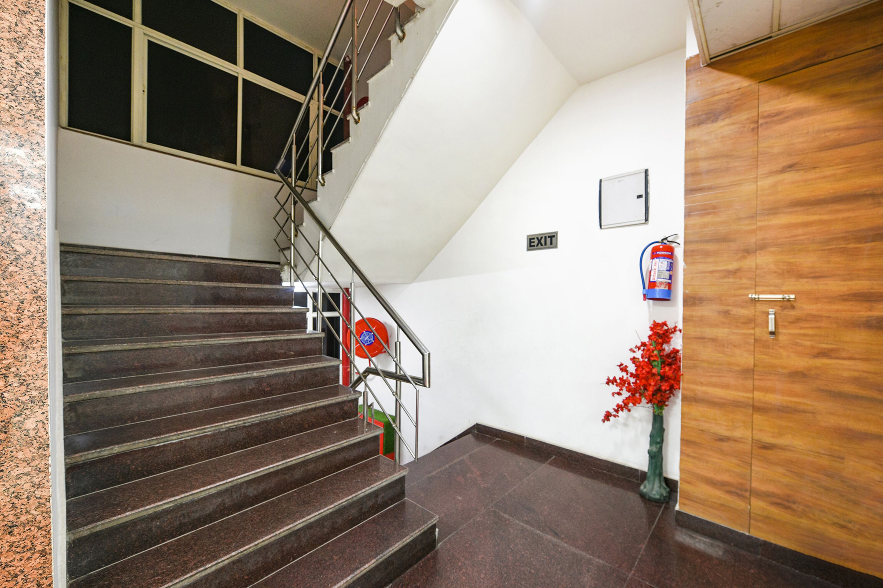 A staircase with metal railings, a fire extinguisher, and a wooden door.