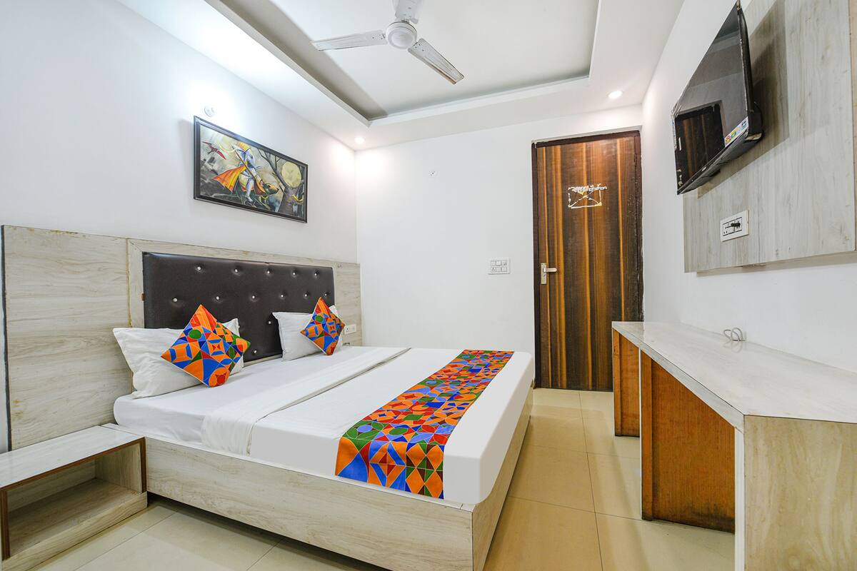 Una habitación de hotel moderna con una cama, un televisor montado en la pared y una puerta que da a otra habitación.