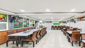 Ein Restaurant mit mehreren Tischen und Sitzecken, einem sauberen Fliesenboden und Speisekarten an den Wänden.
