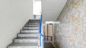 Eine Treppe mit blauer Handlauf, die zu einer Zwischenebene führt.