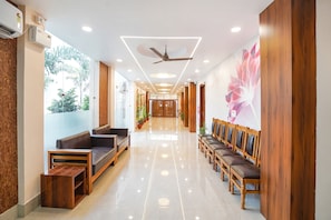 A hotel lobby with a long reception desk, seating area, and a ceiling fan. - Fabhotel Ram Anandam Inn (Faizabad)