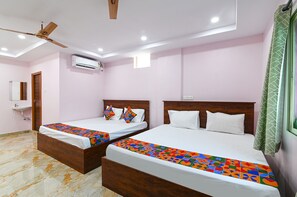 Habitación de hotel con dos camas, ventilador de techo, aire acondicionado y ventana con cortina verde.