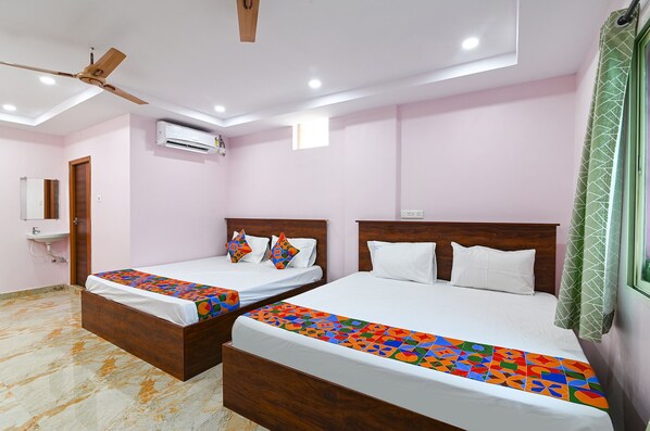 Une chambre d’hôtel avec deux lits, un ventilateur de plafond, un appareil de climatisation et une fenêtre avec un rideau vert.