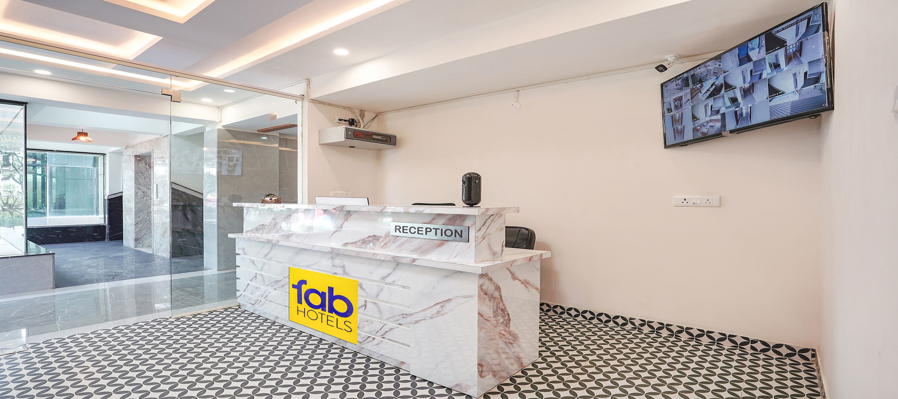 A hotel reception desk with a marble finish, a glass wall, and a tiled floor.
