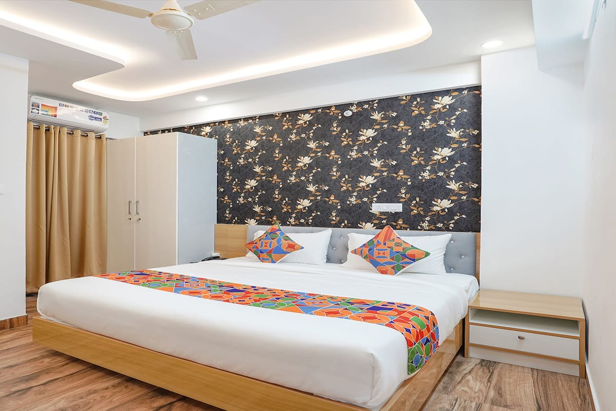 Ein modernes Hotelzimmer mit einem Bett, einem Nachttisch, einem Deckenventilator und einer Wand-Klimaanlage.