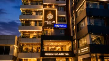 A multi-story hotel with a prominent 'Premium Hotel' sign, a modern facade, and a well-lit entrance.