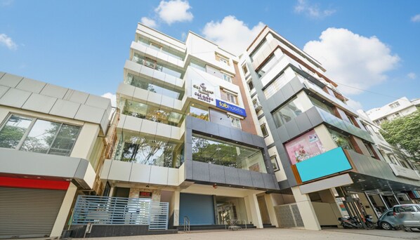 A multi-story building with a 'Fab Hotels' sign, large windows, and a visible storefront. - FabHotel Vasatiya & Suites (Bengaluru)