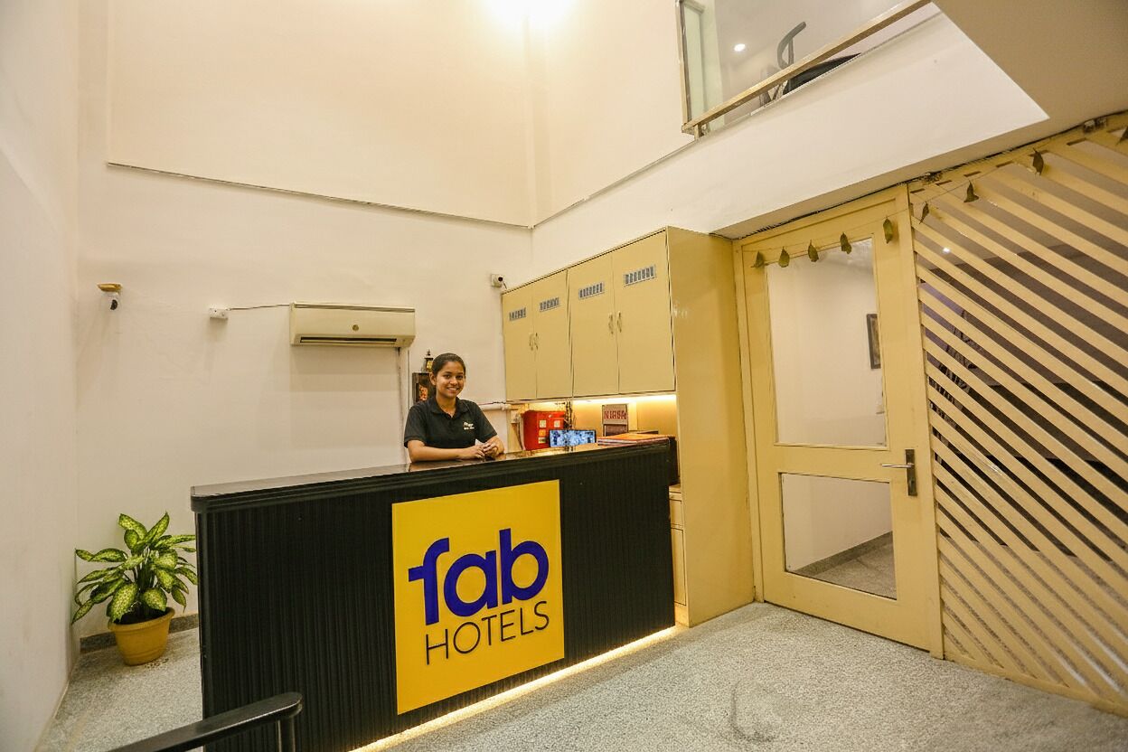 Ein Empfangstresen mit einem Schild für 'fab hotels' und einer Zimmerpflanze auf der linken Seite.