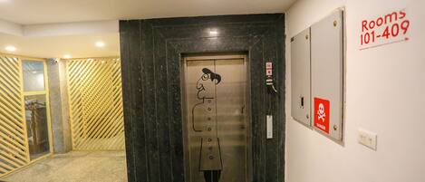 An elevator with a safety sign, a "Rooms 101-409" sign, and a "DANGER" sign on the wall.