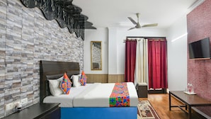 A hotel room with a brick-patterned wall, a bed with a blue mattress, a ceiling fan, a TV on the wall, and a window with red curtains. - Fabhotel The Icon (New Delhi)