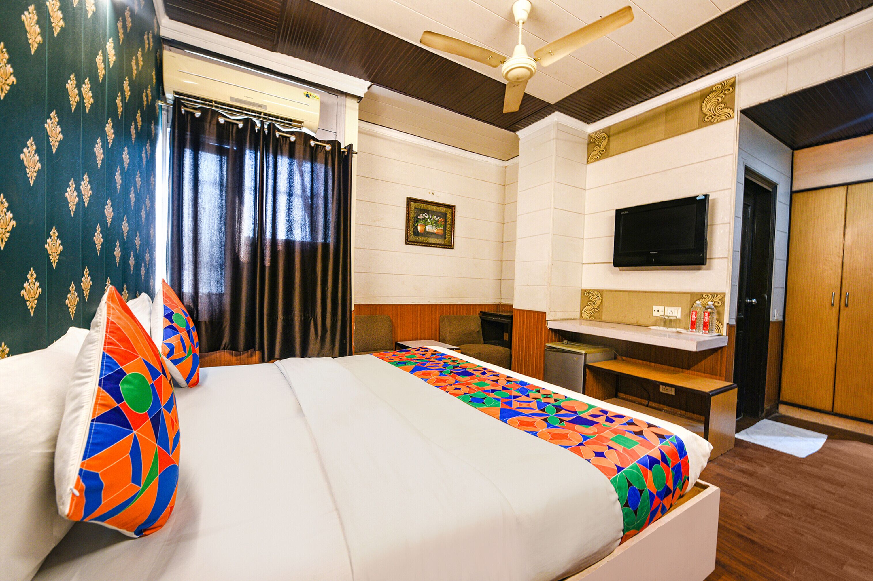 A hotel room with a bed, a desk, a television, and a wardrobe.