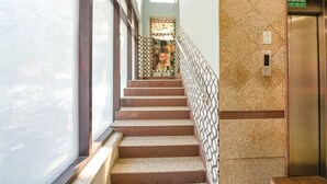 A staircase with a patterned wall and an elevator to the right. - Fabhotel The Icon (New Delhi)