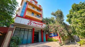A multi-story boutique hotel with a prominent red and white facade, balconies, and lush greenery surrounding the building. - Fabhotel The Icon (New Delhi)