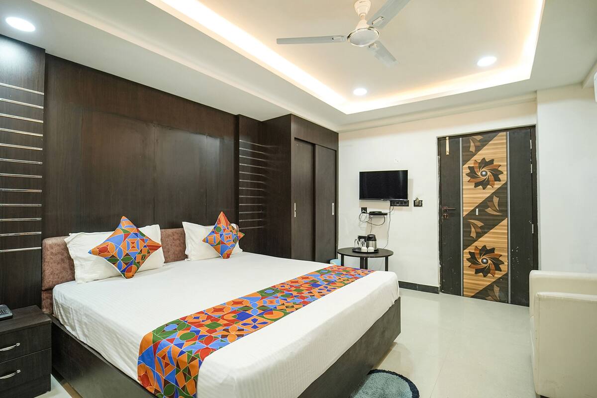 Una habitación de hotel moderna con una cama grande, ventilador de techo, televisor de pantalla plana y una puerta decorativa.