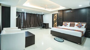 A modern bedroom with a large bed, a desk, and a chair. - Fabhotel Royal Carpet (Patna)
