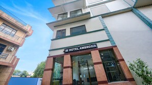 Een hotel genaamd 'HOTEL AMBROSIA' met een moderne gevel, grote ramen en een duidelijke entree.