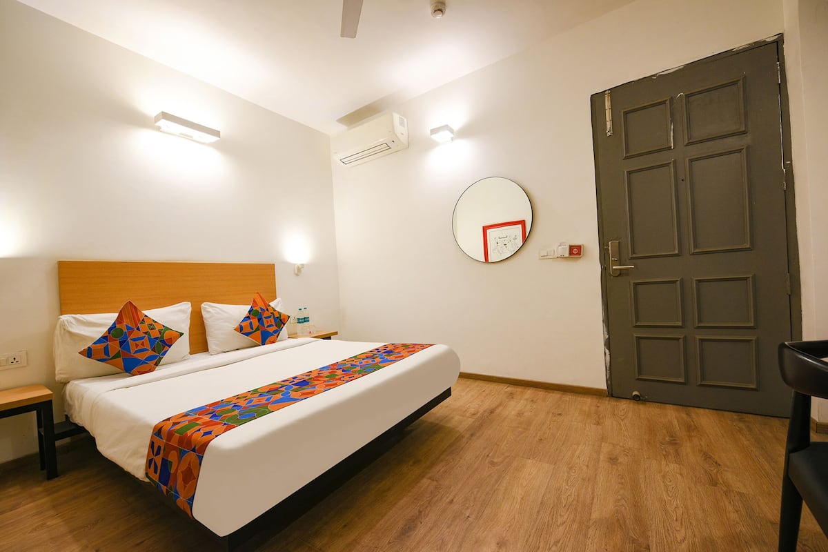 A hotel room with a bed, bedside table, and a door.