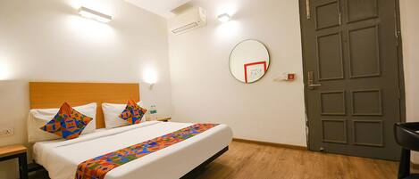 A hotel room with a bed, bedside table, and a door.