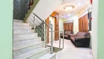 A staircase with a metal railing leading to a landing. There are two sofas and a small table on the landing.
