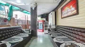A hotel lobby with leather sofas, a Coca-Cola refrigerator, a television, and a mural on the wall.