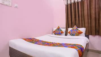 A neatly made bed with a colorful geometric-patterned bedspread and two decorative pillows.