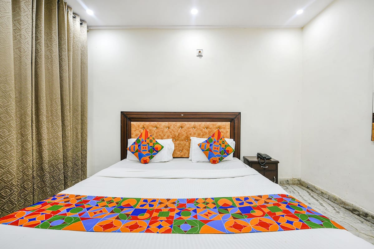 A hotel room with a bed, a nightstand, and a patterned curtain.