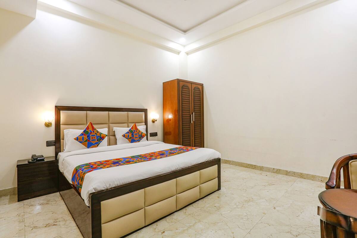 Une chambre bien rangée, avec un lit, des tables de chevet, une armoire et une chaise.