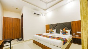 Une chambre à coucher comprenant un lit, un bureau, une armoire et un appareil de climatisation.