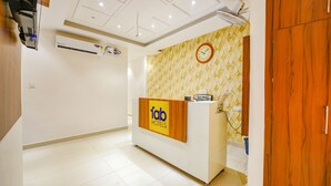 Un comptoir d’accueil avec une enseigne indiquant « Tab Hotels », une horloge et un appareil de climatisation fixé au mur.