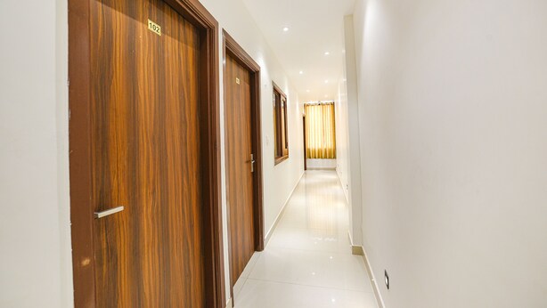 Un couloir avec des portes en bois, un sol carrelé et un plafond clair.