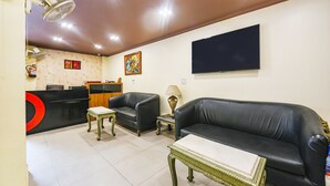Un soggiorno con divano, due poltrone, un tavolino, televisore e una scrivania della reception.