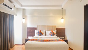 Ein Hotelzimmer mit einem großen Bett, zwei Nachttischen, einem Fenster mit Vorhängen und einer Decken-Klimaanlage.