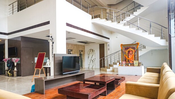 Eine geräumige Lobby mit moderner Treppe, einem Flachbildfernseher, einem roten Staffelei und einer Statue.