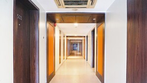 Ein Hotelkorridor mit Holztüren, Fliesenboden und einer Decke mit eingelassener Beleuchtung.