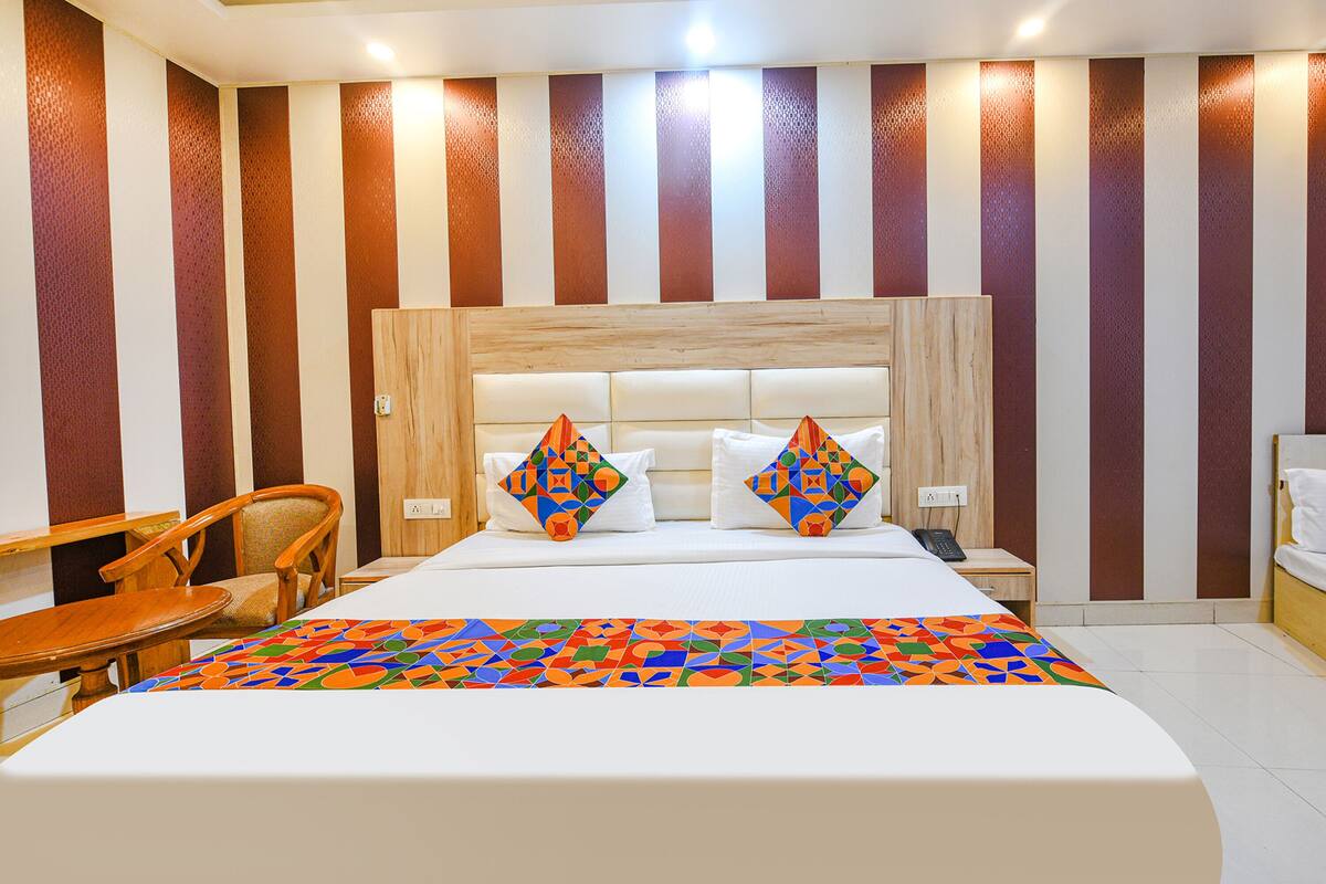 A hotel room with a large bed, two pillows, a bedside table with a phone, and a chair.