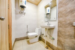 Un baño pequeño y limpio con inodoro, lavamanos y un espejo sobre el lavamanos.