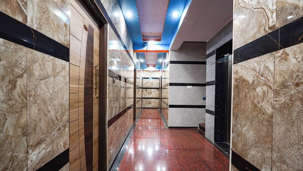 Ein moderner Korridor mit Marmorwänden, einem roten Fliesenboden und einer blauen Decke.