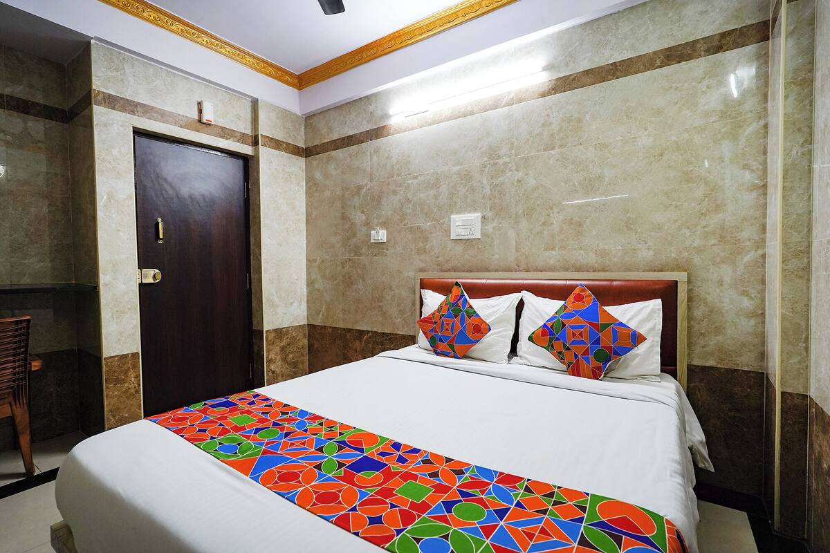 A hotel room with a bed, a wooden door, and a bathroom visible to the left.
