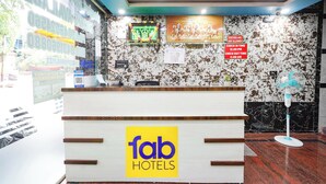 Ein Hotelrezeptionstresen mit Marmorwand, einem Empfangsschild und einer Schilder mit den Check-in- und Check-out-Zeiten.
