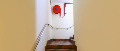 A staircase with a metal handrail and a red fire hose reel mounted on the wall.