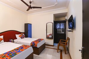 Habitación de hotel con dos camas, ventilador de techo, televisor y espejo.