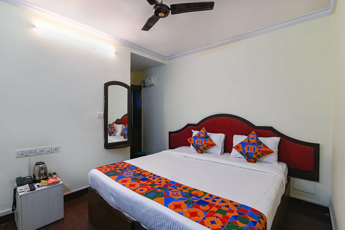 A hotel room with a bed, a nightstand, a ceiling fan, and a mirror.